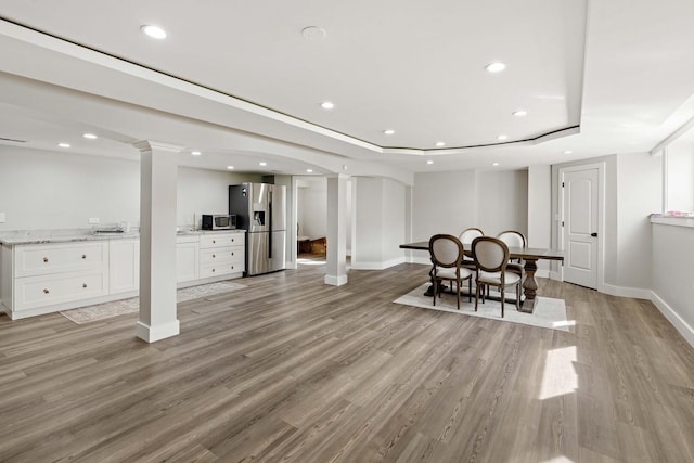 basement with recessed lighting, light wood-style flooring, and stainless steel fridge with ice dispenser