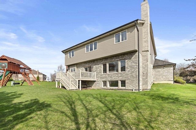 back of property featuring a chimney, a yard, brick siding, a playground, and stairs
