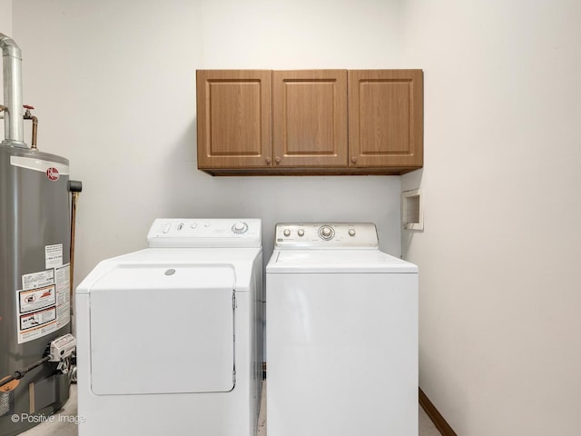 clothes washing area featuring gas water heater, separate washer and dryer, and cabinet space