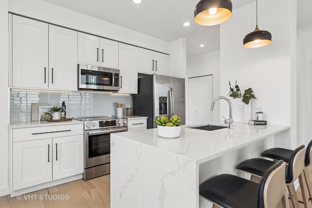 421 W Huron St Unit 1504, Chicago, IL 60654 - kitchen featuring appliances with stainless steel finishes, decorative backsplash, white cabinets, light stone countertops, and hanging light fixtures