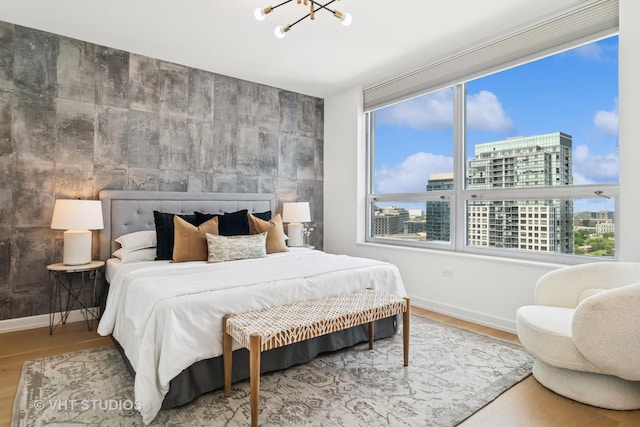 421 W Huron St Unit 1504, Chicago, IL 60654 - bedroom with a chandelier, an accent wall, wood finished floors, and a city view