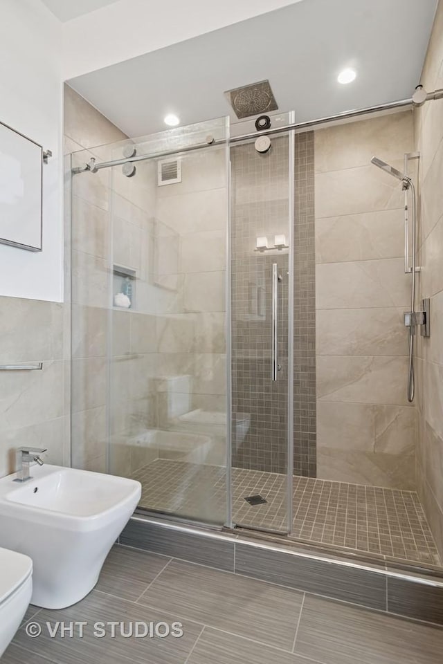 421 W Huron St Unit 1504, Chicago, IL 60654 - bathroom featuring a stall shower, a bidet, tile patterned floors, recessed lighting, and tile walls