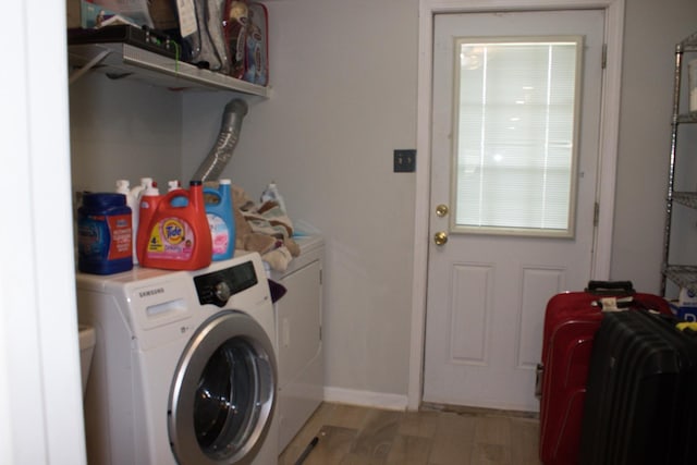 washroom with washing machine and dryer, baseboards, light wood finished floors, and laundry area