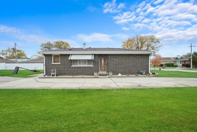 back of property featuring fence, a lawn, and brick siding