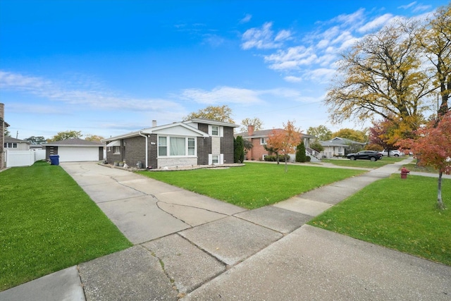 view of front of house with brick siding, fence, a detached garage, and a front yard