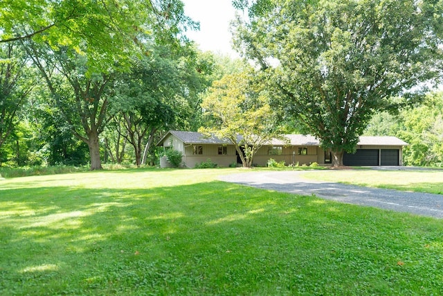 view of yard featuring aphalt driveway and a garage