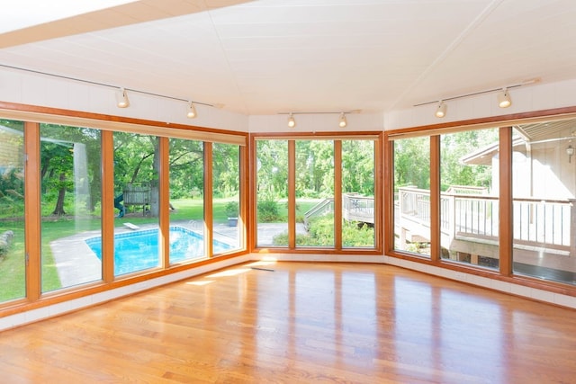 unfurnished sunroom with rail lighting and wood finished floors