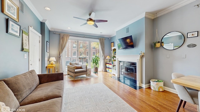 living area featuring ornamental molding, a ceiling fan, wood finished floors, and visible vents