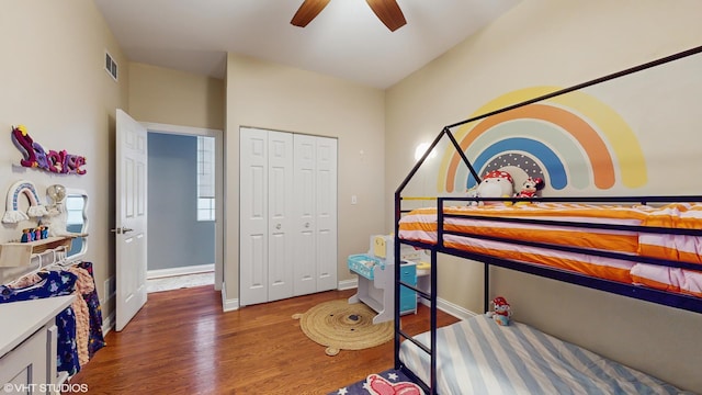 bedroom with ceiling fan, baseboards, wood finished floors, visible vents, and a closet