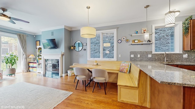 kitchen featuring crown molding, ceiling fan, light stone counters, light wood finished floors, and tasteful backsplash