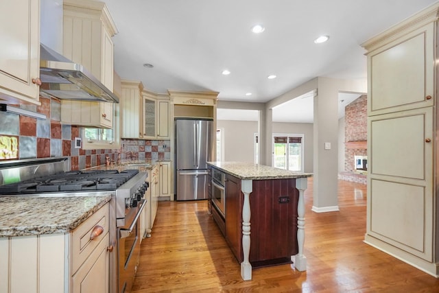 4240 Kingshill Cir, Naperville, IL 60564 - kitchen featuring stainless steel appliances, cream cabinetry, light wood-style flooring, tasteful backsplash, and recessed lighting