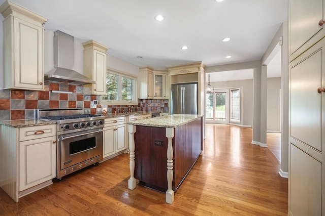 4240 Kingshill Cir, Naperville, IL 60564 - kitchen featuring stainless steel appliances, cream cabinetry, wall chimney exhaust hood, light wood-type flooring, and recessed lighting