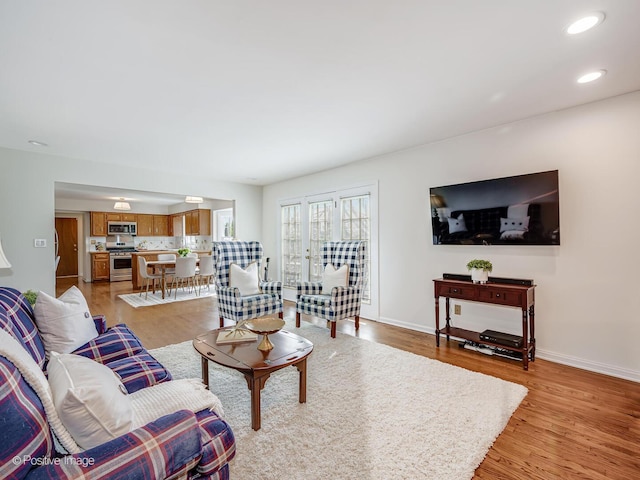 living room featuring recessed lighting, baseboards, and light wood-style floors