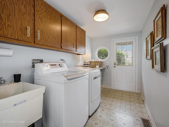 laundry room featuring baseboards, light floors, a sink, cabinet space, and independent washer and dryer