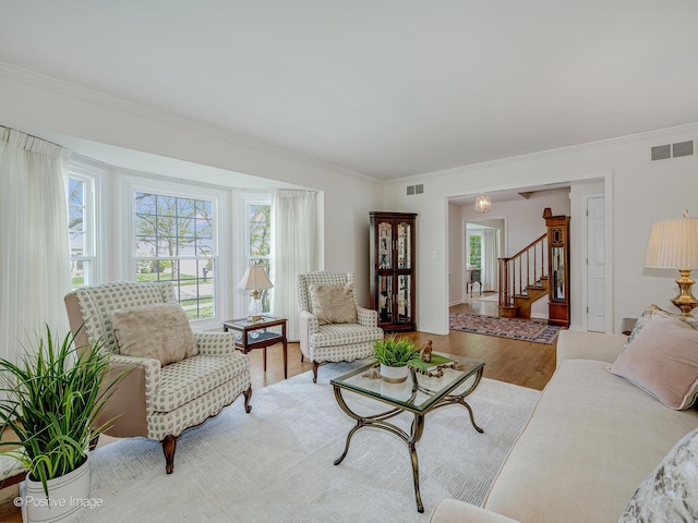 living room featuring visible vents, crown molding, wood finished floors, and stairway