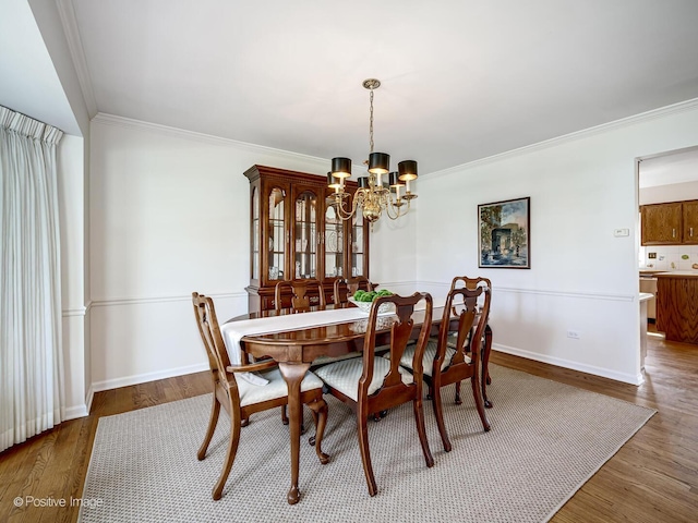 dining area featuring baseboards, an inviting chandelier, ornamental molding, and wood finished floors