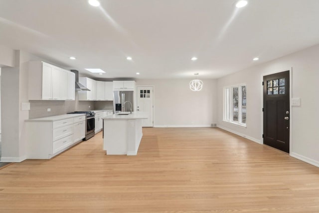 kitchen with wall chimney range hood, appliances with stainless steel finishes, light wood-type flooring, and recessed lighting
