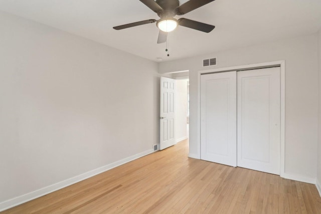 unfurnished bedroom featuring light wood-style flooring, baseboards, visible vents, a ceiling fan, and a closet