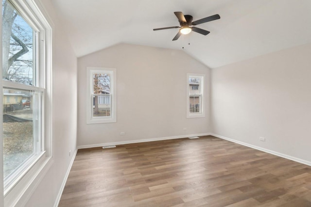 unfurnished room featuring a wealth of natural light, a ceiling fan, wood finished floors, and lofted ceiling