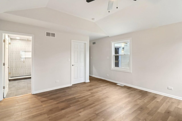 unfurnished bedroom featuring vaulted ceiling, wood finished floors, visible vents, and baseboards