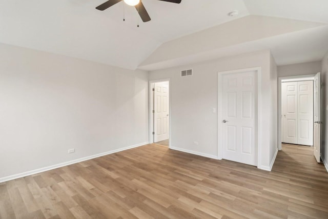 unfurnished bedroom featuring light wood-type flooring, ceiling fan, baseboards, lofted ceiling, and visible vents