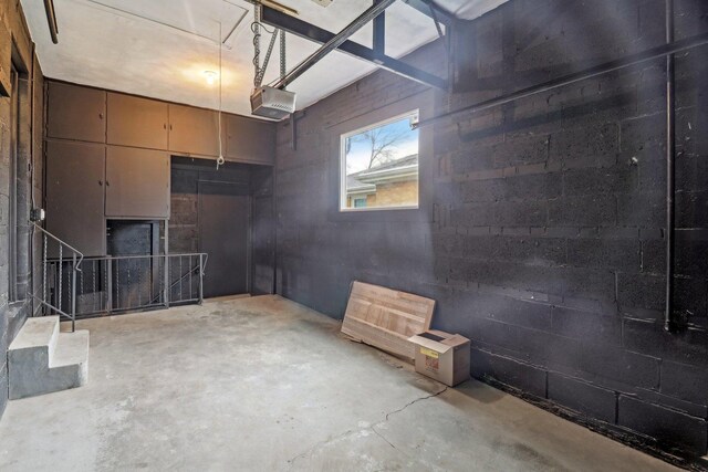 garage featuring a garage door opener and concrete block wall