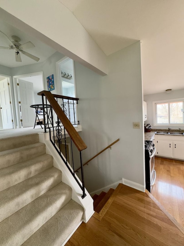 stairway featuring baseboards, hardwood / wood-style flooring, and ceiling fan