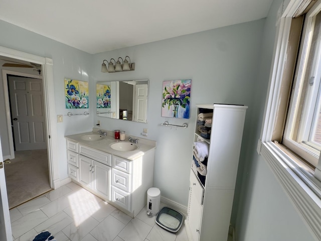 bathroom with baseboards, double vanity, and a sink