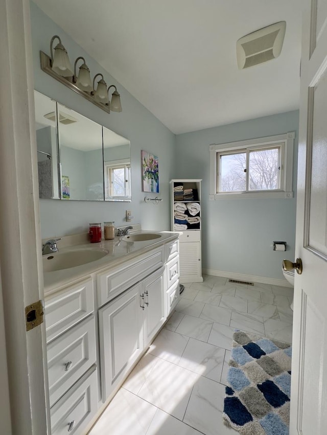full bath with a sink, marble finish floor, double vanity, and toilet