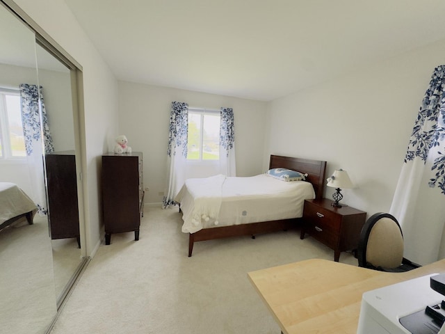 bedroom with a closet, light colored carpet, and baseboards