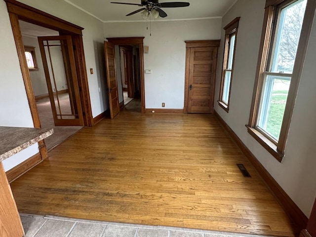 spare room featuring baseboards, a ceiling fan, visible vents, and light wood-style flooring