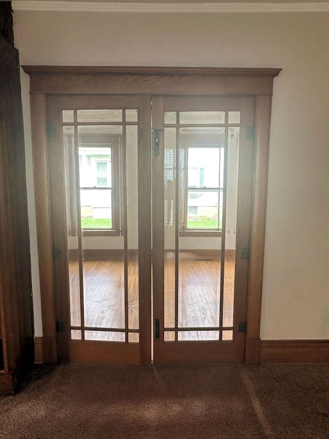 doorway to outside with baseboards, crown molding, and carpet floors