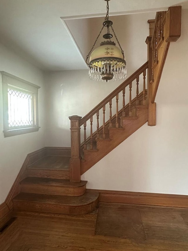 stairs featuring a chandelier, wood finished floors, and baseboards