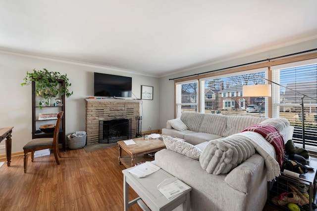 living room featuring baseboards, a stone fireplace, wood finished floors, and ornamental molding