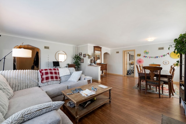 living room with arched walkways, ornamental molding, and visible vents