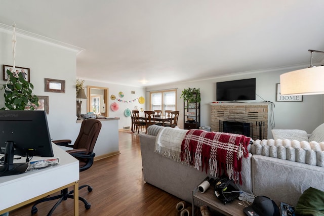 living area featuring wood finished floors, crown molding, baseboards, and a stone fireplace