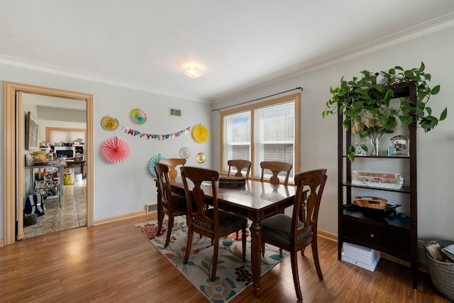 dining room featuring baseboards, crown molding, wood finished floors, and visible vents