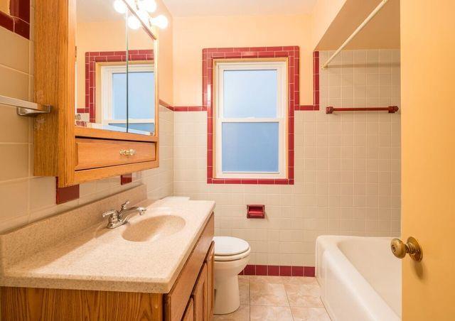 full bath featuring tile patterned floors, toilet, vanity, tub / shower combination, and tile walls