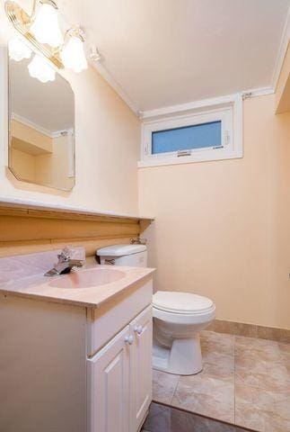 bathroom with toilet, crown molding, vanity, and baseboards