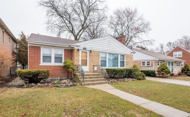 bungalow-style home with a chimney, brick siding, and a front yard