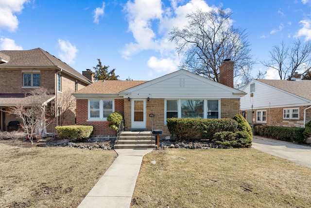 view of front of house featuring brick siding, a front lawn, and a chimney