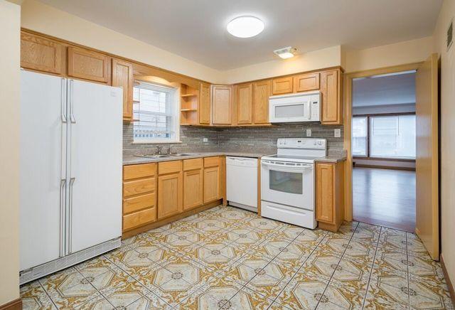 kitchen with light countertops, tasteful backsplash, a healthy amount of sunlight, and white appliances
