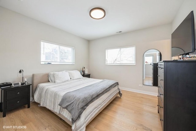 bedroom with baseboards, multiple windows, light wood finished floors, and visible vents