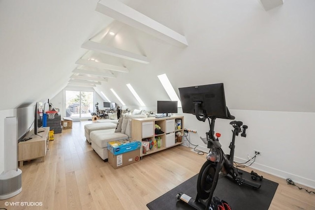 exercise area featuring baseboards, light wood-type flooring, and lofted ceiling