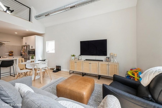 living area featuring a high ceiling and light wood-style floors