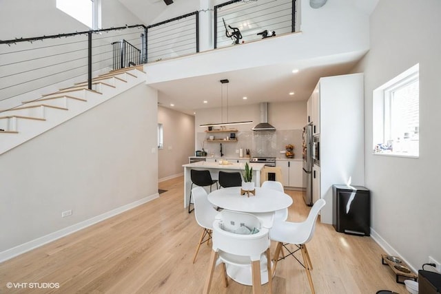 dining room featuring baseboards, high vaulted ceiling, stairway, light wood-type flooring, and recessed lighting