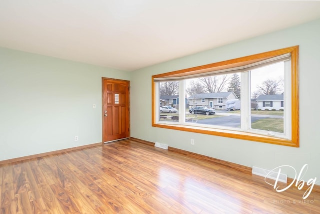 spare room with baseboards, wood finished floors, and visible vents