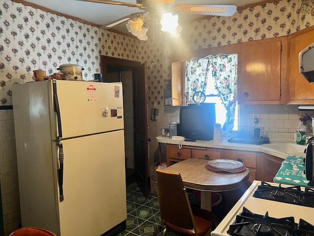 117 W 103rd Pl, Chicago, IL 60628 - kitchen featuring freestanding refrigerator, wallpapered walls, brown cabinetry, light countertops, and a ceiling fan