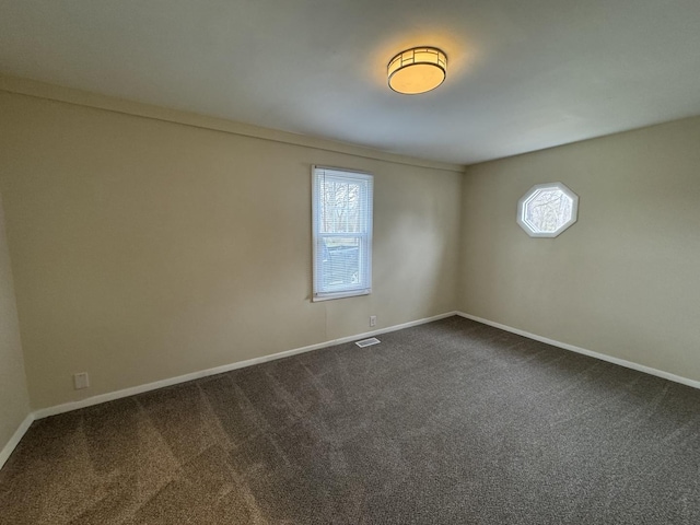 spare room with dark colored carpet and baseboards