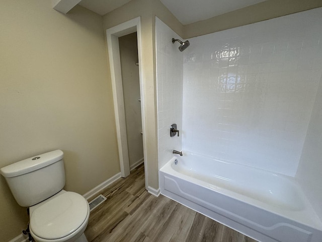 full bath with toilet, wood finished floors, visible vents, tub / shower combination, and baseboards